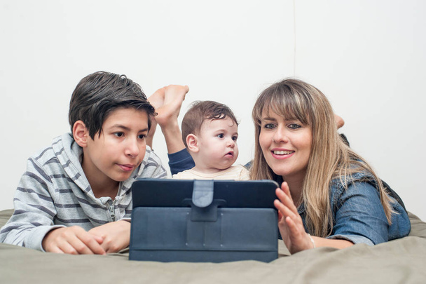 вид спереду щасливої сім'ї, використовуючи планшет у ліжку
. - Фото, зображення