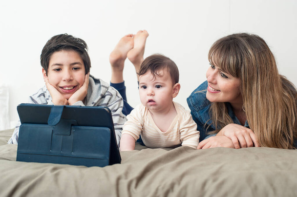 вид спереду щасливої сім'ї, використовуючи планшет у ліжку
. - Фото, зображення