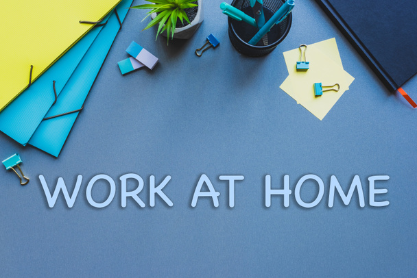 Draufsicht auf Schreibwaren und Arbeit zu Hause Schriftzug auf blauer Fläche - Foto, Bild