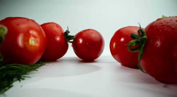 Czerwone pomidory na białym, izolowanym tle. Strzał z niskiego kąta - Zdjęcie, obraz