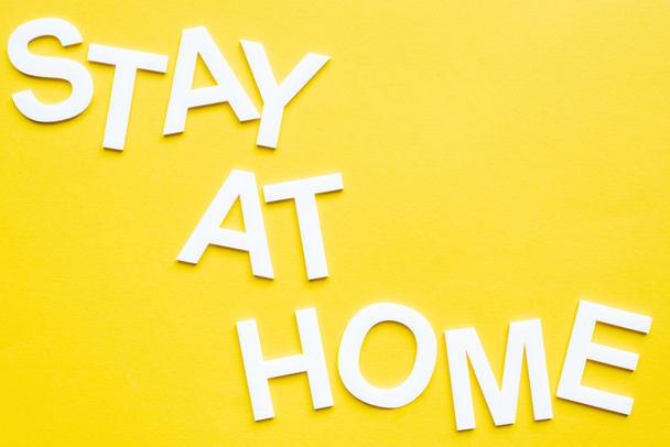 Top view of lettering stay at home on yellow surface - Foto, Bild