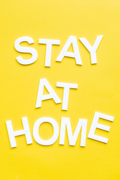 Top view of stay at home white lettering on yellow background - Photo, image