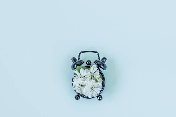Spring and summer time from cherry flowers and a clock on a blue background. Flat lay, top view. Banner. - Foto, Bild