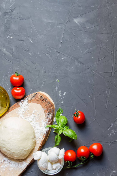 Raw ingredients for pizza on the chalkboard with copy space, dough, tomatoes, mozzarella, basil, vertical photo - Foto, Imagen