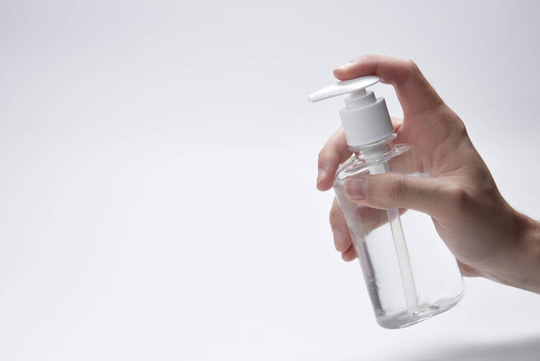 Le doigt pousse une bouteille ou un récipient avec du liquide, de la crème ou de l'antiseptique sur fond blanc
. - Photo, image