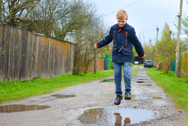 Boy child runs into a wet puddle. Funny walk. - Foto, Bild