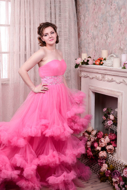 όμορφη μελαχρινή σε ένα πολυτελές ροζ φόρεμα - Φωτογραφία, εικόνα