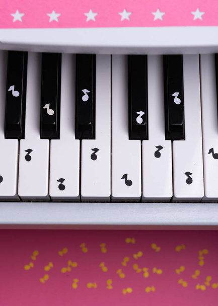 Kağıt notalı beyaz oyuncak piyano. müzik piyano konsepti. Yukarıdan bak. Beyaz, siyah ve sarı notalar. - Fotoğraf, Görsel