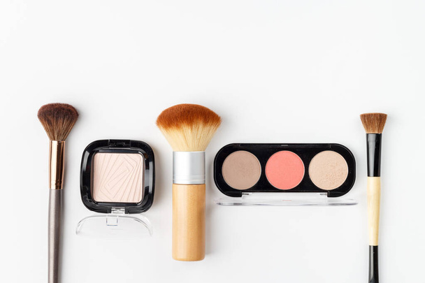 Makeup brushes of different sizes and makeup powder on a white background. Top view. - Photo, Image