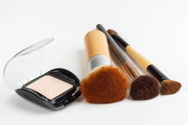 Makeup brushes of different sizes and makeup powder on a white background - Photo, Image