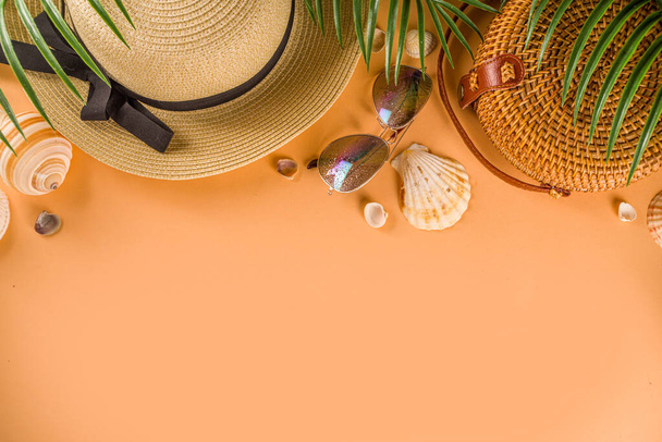 Verão moderno flat-lay com roupa de moda feminina - chapéu de palha, saco de bambu, óculos de sol, em fundo de pêssego com ramos de palma, vista superior, espaço de cópia, flat lay. Moda de verão, conceito de férias
 - Foto, Imagem