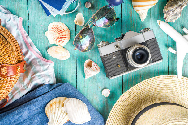 Bright  summer flat-lay background. Old blue wooden background with with summer woman clothes, sun glasses, hat, camera, passports and vacation tickets - Photo, Image
