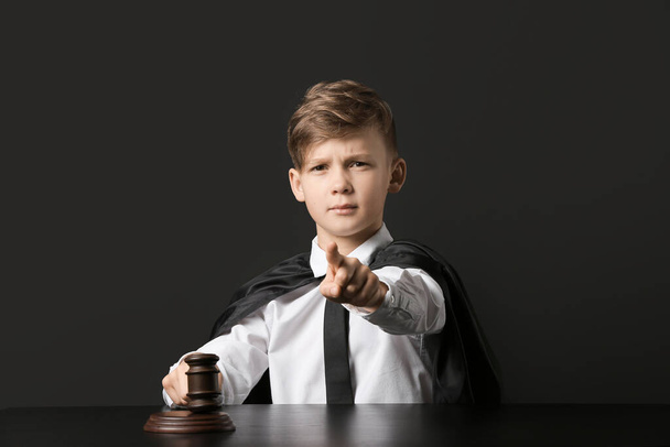 Προσωπογραφία του μικρού δικαστή κάθεται στο τραπέζι σε σκούρο φόντο - Φωτογραφία, εικόνα