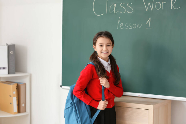 Aranyos kis tanuló a táblánál az osztályteremben. - Fotó, kép