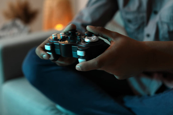 Afro-Amerikaanse tiener jongen spelen video game thuis in de avond, close-up - Foto, afbeelding