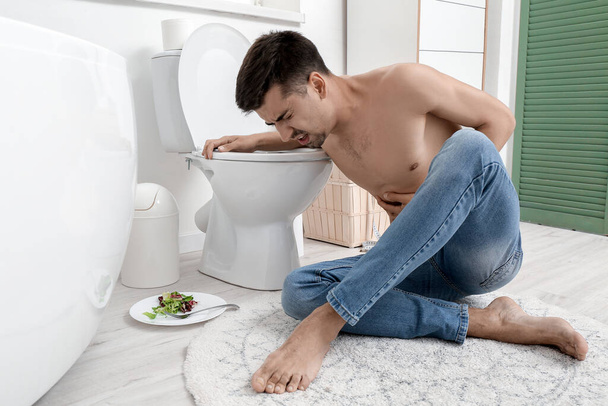 Young man suffering from anorexia near toilet bowl at home - Photo, Image