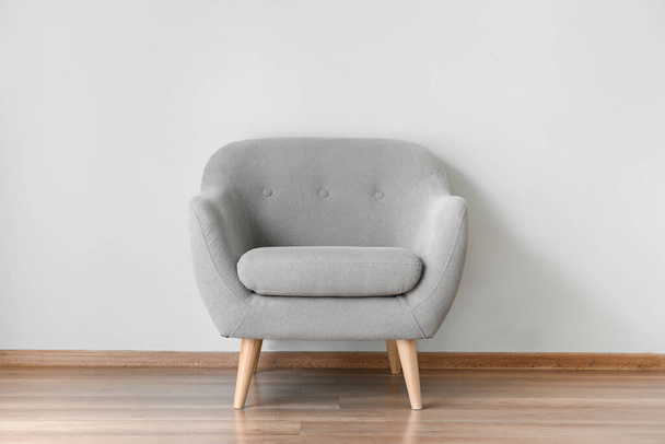 Cómodo sillón cerca de la pared gris en la habitación
 - Foto, Imagen