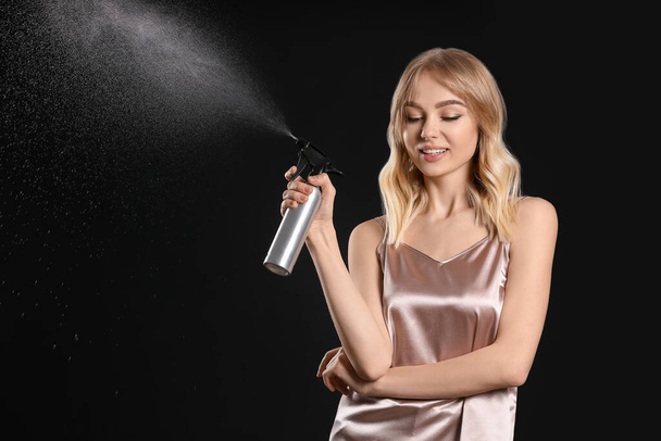 Beautiful young woman with hair spray on dark background - Fotografie, Obrázek