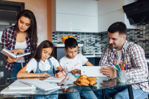 All family  doing homework for school, while sitting at kitchen table at home, togetherness time. - Fotoğraf, Görsel