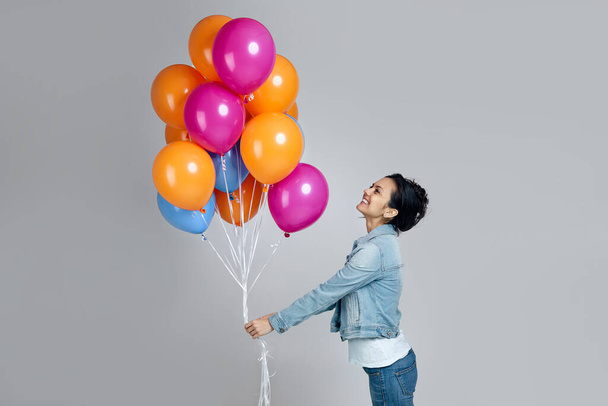 girl in denim posing with bright colorful air balloons - Фото, изображение