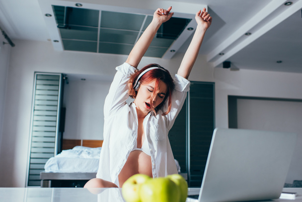 beautiful girl listening music in headphones, dancing and singing at home with laptop on quarantine - 写真・画像