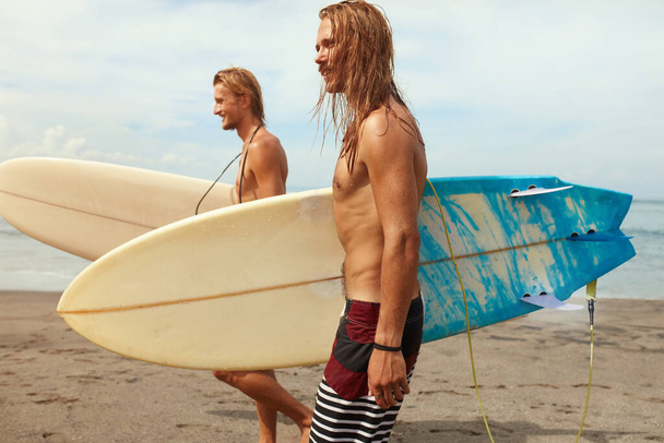 Surfing. Handsome Surfers With Surfboards. Young Men Walking On Ocean Beach. Active Lifestyle, Water Sport On Beautiful Sea Background. - 写真・画像