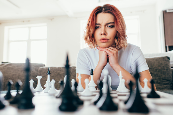 Nachdenkliches Mädchen spielt Schach über Selbstisolierung, selektive Fokussierung - Foto, Bild