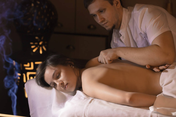 Beautiful girl in a massage parlor for back health treatments and aromatherapy - Fotó, kép
