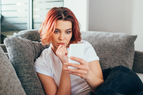 gyönyörű gondolkodó lány használja okostelefon otthon során elszigeteltség  - Fotó, kép