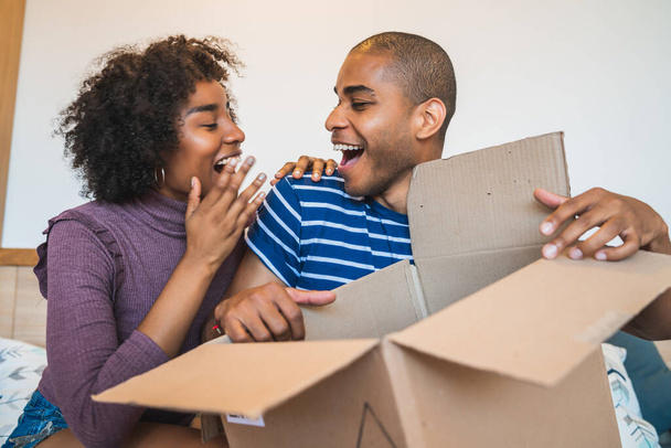 Portrait of happy young latin couple opening a package at home. Delivery, shipping and postal service concept. Buy online and stay at home. Covid-19 Quarantine. - Foto, Imagem