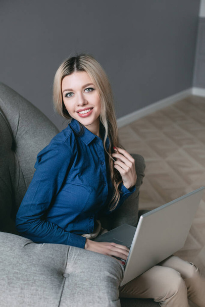 Happy pretty woman using laptop sitting on cosy sofa. Businesswoman typing business message to colleague. - Zdjęcie, obraz