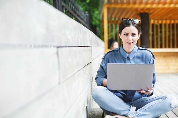 Student girl with laptop in the working space outdoors. Female freelancer. - 写真・画像