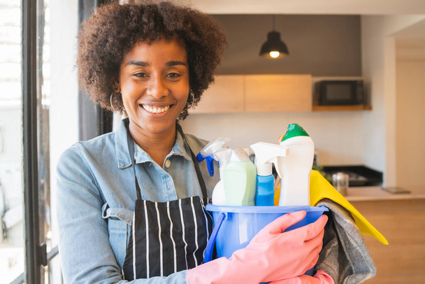 Portrait of young afro woman cleaning and disinfecting her house during coronavirus pandemic. Stay safe and stay at home. Prevention of COVID-19 infection. Quarantine concept. - Фото, изображение
