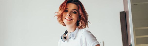 schönes lächelndes Mädchen mit Kopfhörern während der Selbstisolierung - Foto, Bild