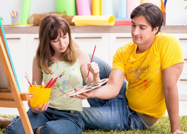 Fiatal pár élvezi a festést otthon - Fotó, kép