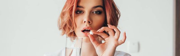 krásná dívka drží pilulku a sklenici vody doma na karanténě, panoramatický koncept - Fotografie, Obrázek