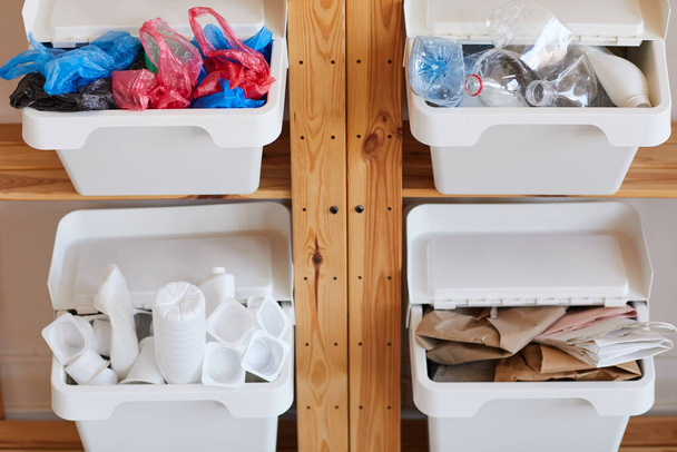 Hintergrundbild von Holzregalen mit vier Kunststoffbehältern zur Abfalltrennung zu Hause, für Recycling vorbereitet, Kopierraum - Foto, Bild