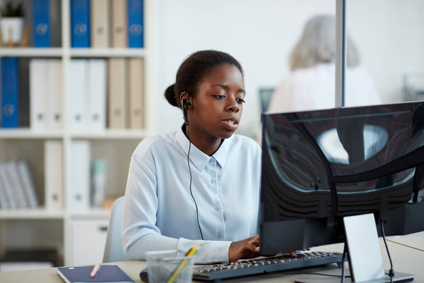 Portrait of African-American woman wearing headset while working as call center operator in office interior, copy space - Foto, imagen