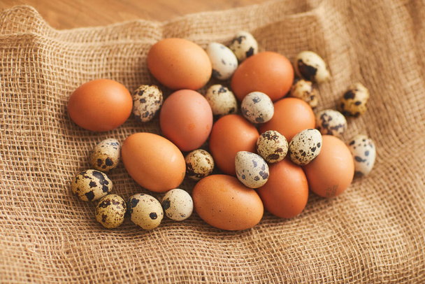 Backgroiund image of farmers chicken eggs and quail eggs in burlap wrapping, copy space - Photo, Image