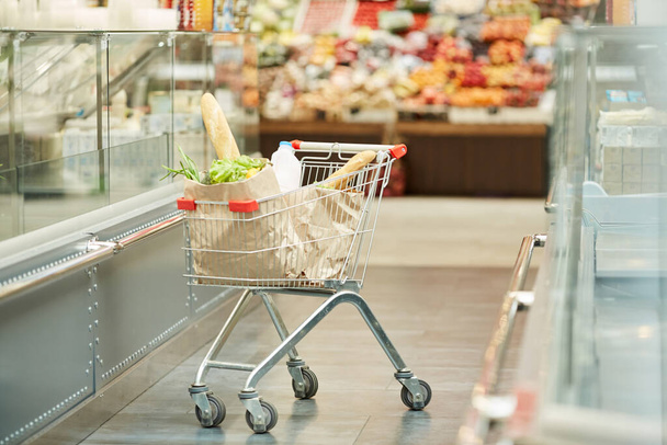 Hintergrundbild von Einkaufswagen mit Lebensmitteln, die im Supermarkt stehen, Kopierraum in voller Länge - Foto, Bild