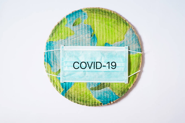 Dünya gezegeni tıbbi bir maskeyle. Dünya çapında en çok aranan Coronavirus covid-19 koruma maddesi. - Fotoğraf, Görsel