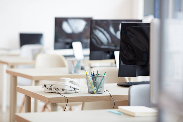 Hintergrundbild leerer Büroarbeitsplätze hintereinander mit Fokus auf verkabeltes Telefon am Schreibtisch im Call Center, Kopierraum - Foto, Bild