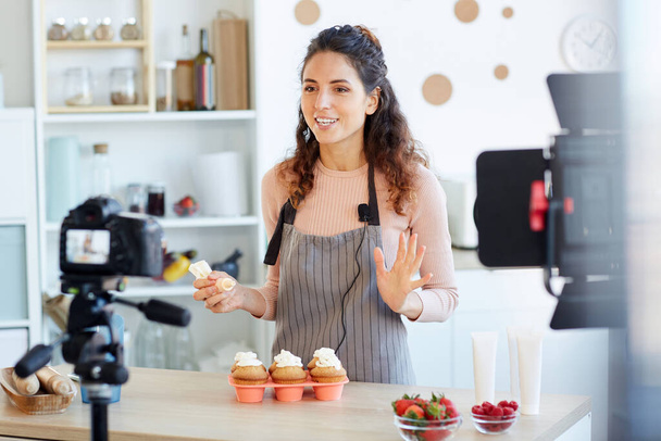 Positive junge erwachsene Frau schießt hausgemachte Cupcakes Video-Tutorial für ihren Food-Blog-Kanal - Foto, Bild