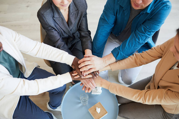Visão acima em grupo multi-étnico de pessoas que empilham as mãos enquanto se motivam mutuamente no círculo de grupo de apoio - Foto, Imagem