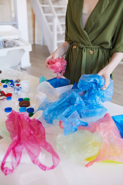 Retrato de sección media de la mujer moderna que clasifica los residuos plásticos en el hogar antes de reciclar, espacio de copia
 - Foto, imagen