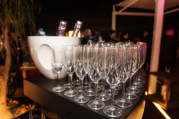 Sparkling wine bottle in the ice bucket and wine glasses in a restaurant setting - Photo, Image