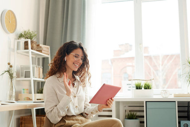 Jovem mulher moderna vestindo elegante ter videoconferência com seus colegas de trabalho enquanto ficar em casa
 - Foto, Imagem