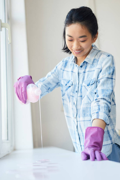 Cintura até retrato de jovem mulher asiática sorrindo alegremente enquanto lava janelas e desfruta de limpeza de primavera, espaço de cópia
 - Foto, Imagem