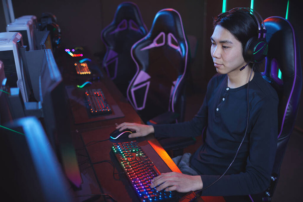 Высокоугловой портрет молодого азиата, играющего в видеоигры на стуле киберспорта, копировальное пространство - Фото, изображение