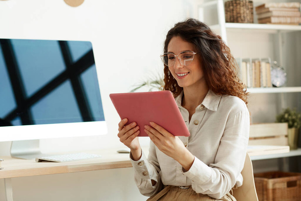 Горизонтальний середній портрет молодої бізнес-леді в окулярах з використанням планшетного комп'ютера для роботи
 - Фото, зображення